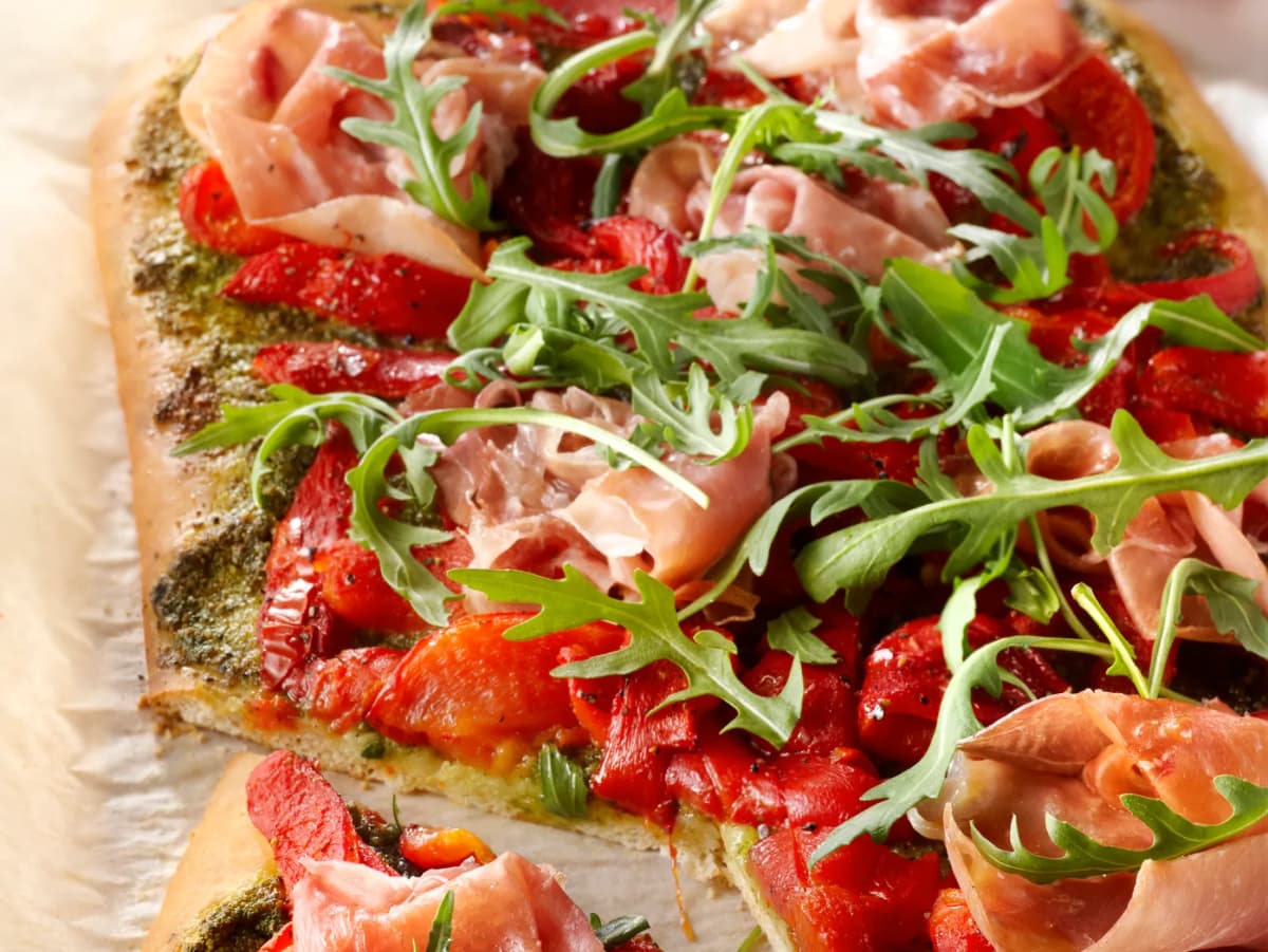 Pizza met rauwe ham, paprika en rucola